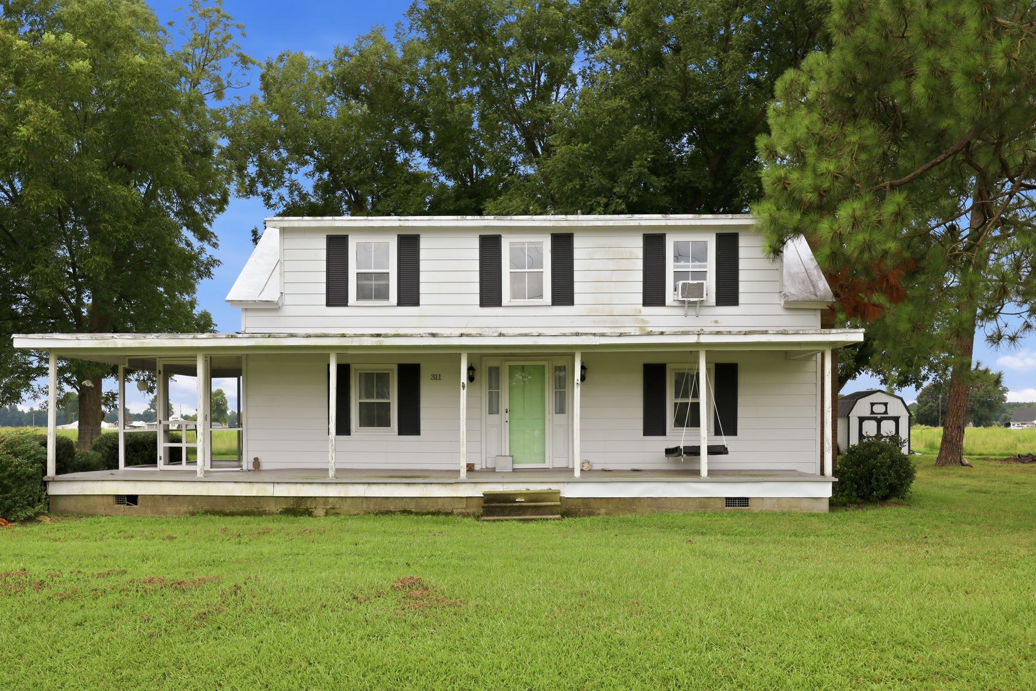 A classic two-story farmhouse with wraparound porch in outlying Chowan County