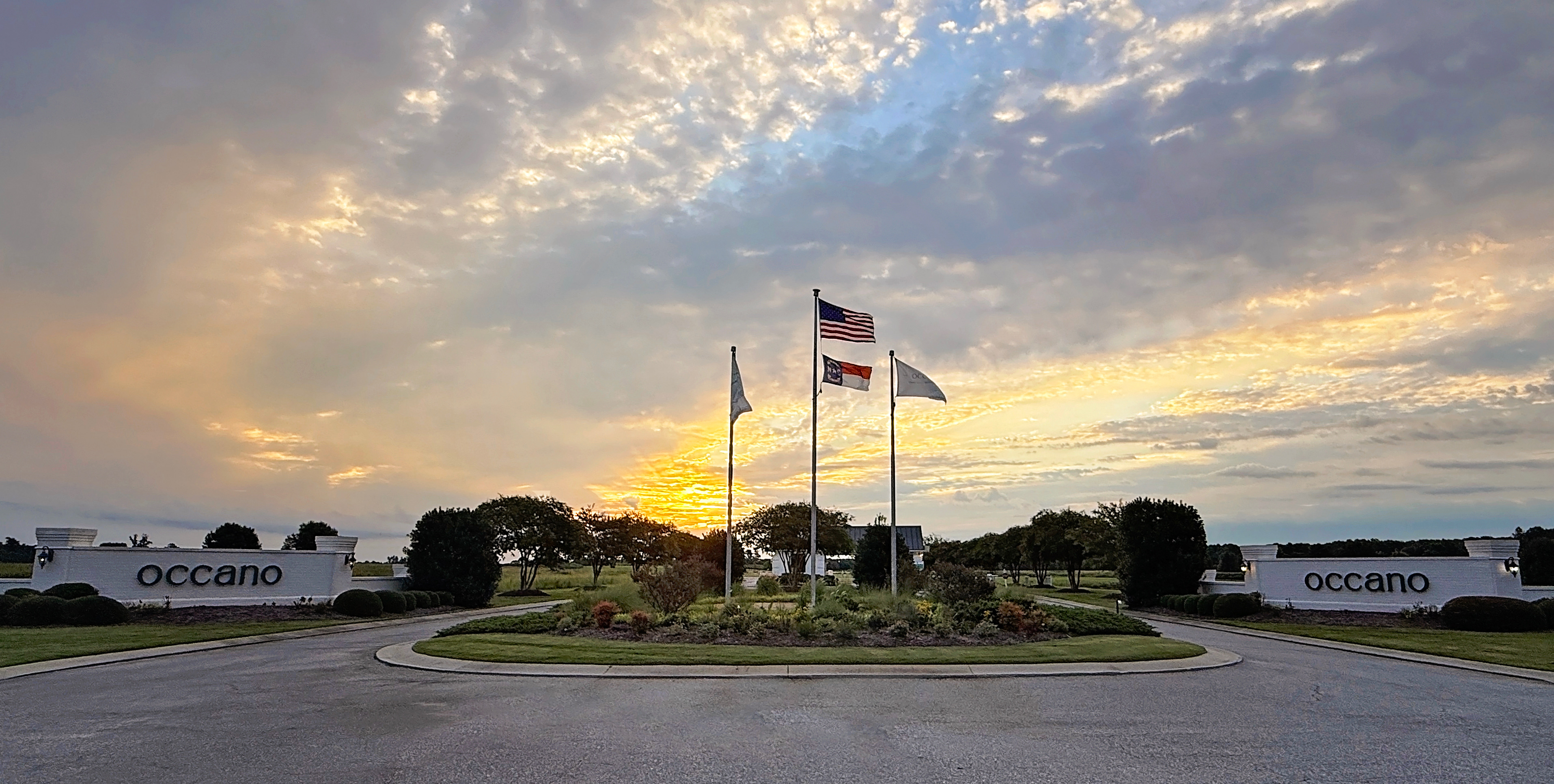 Occano entrance roundabout with American, North Carolina, and Occano flags at sunset